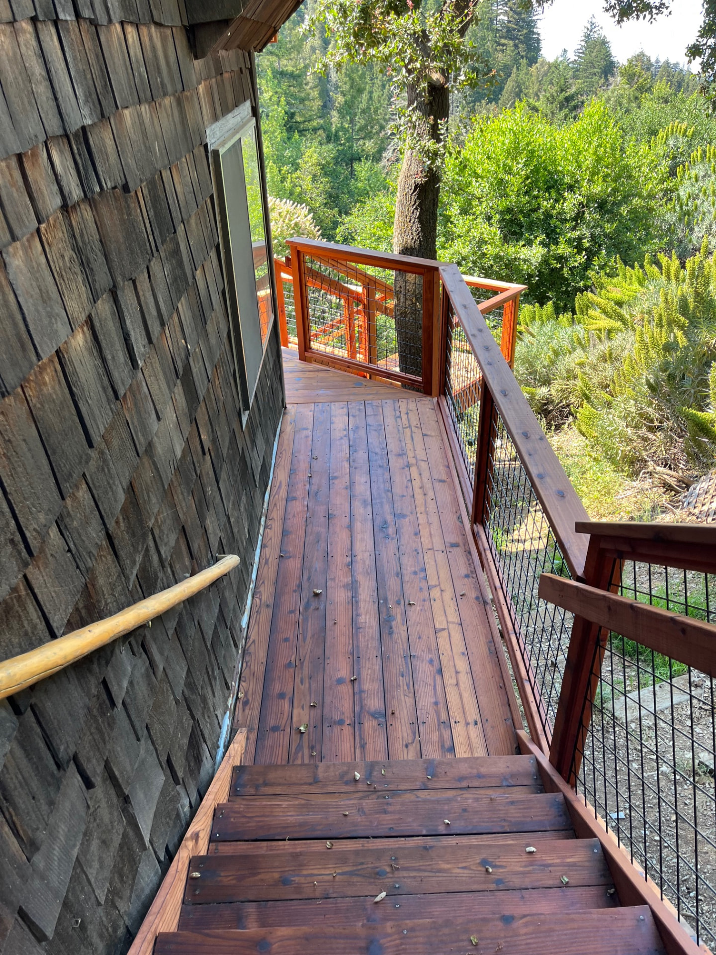 Stained deck walkway and stairs alongside a shingled home