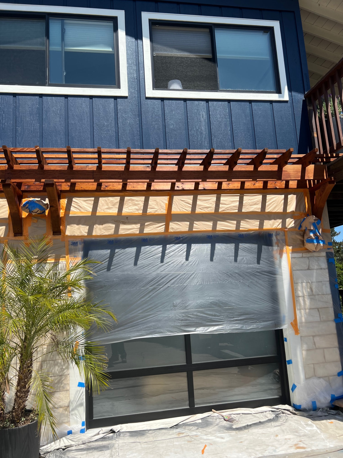 Stained trellis over a masked garage during exterior repaint