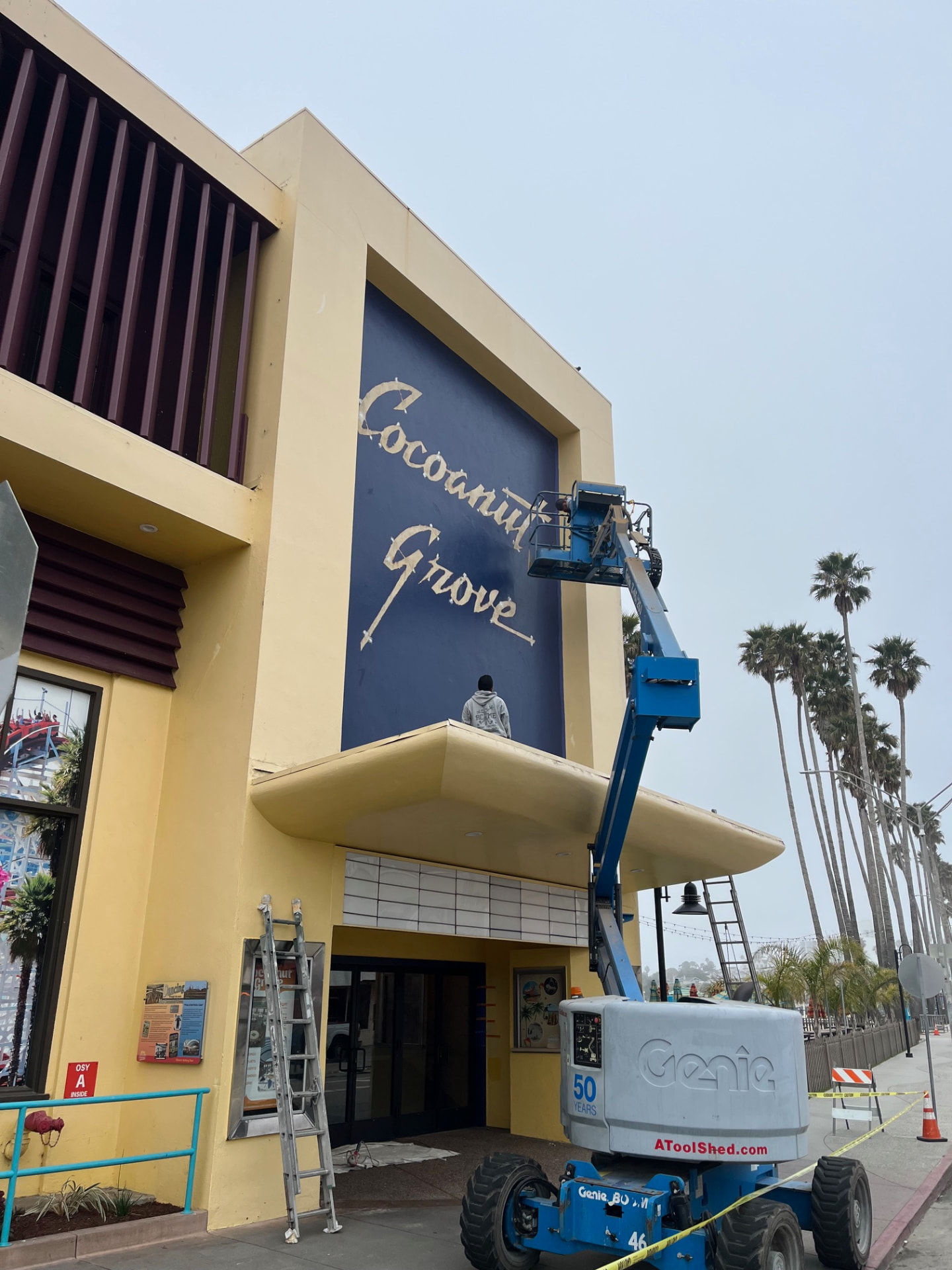 Crew repainting the Cocoanut Grove facade from a boom lift