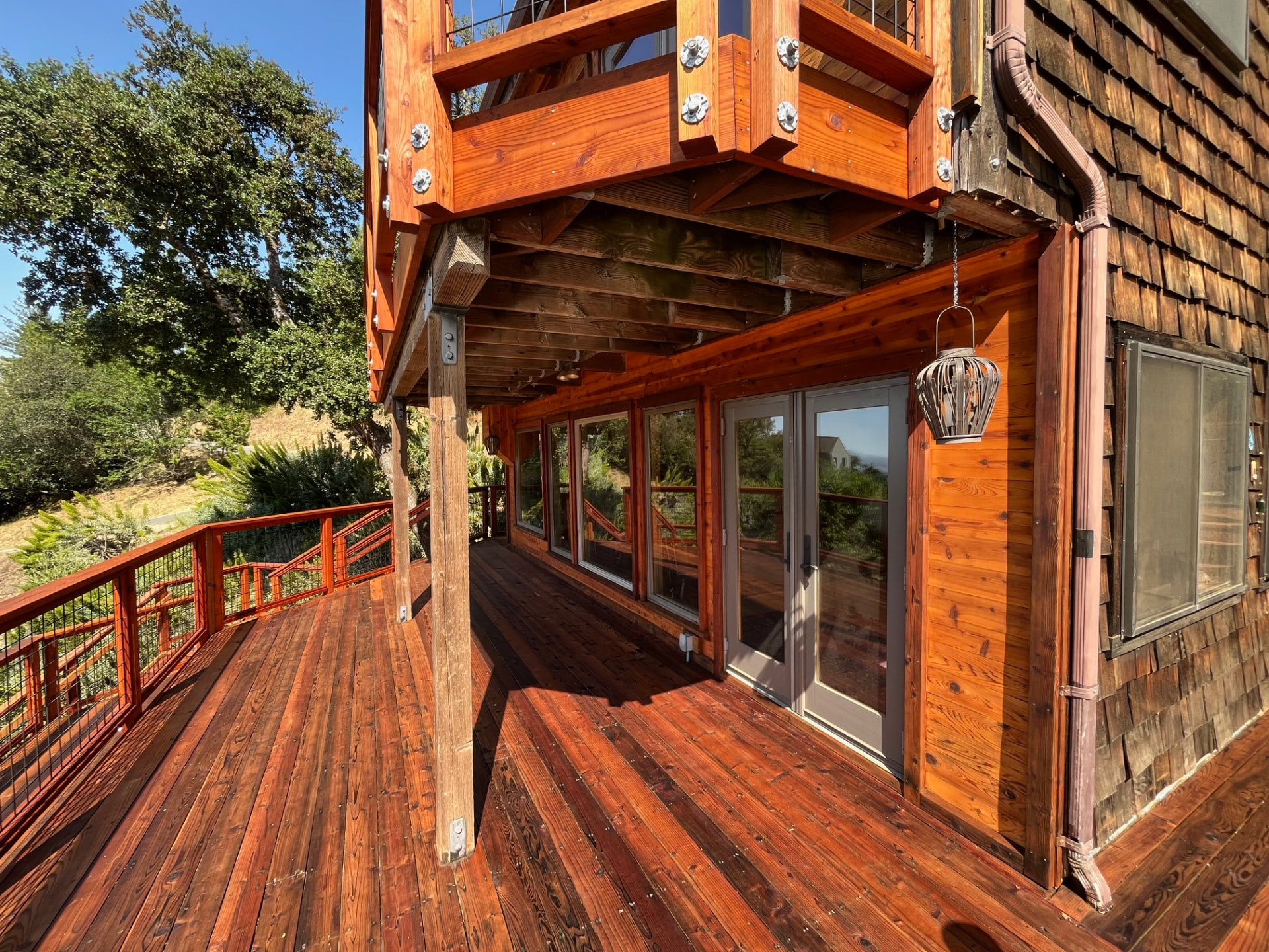Restained redwood deck and covered porch with hog-wire railing