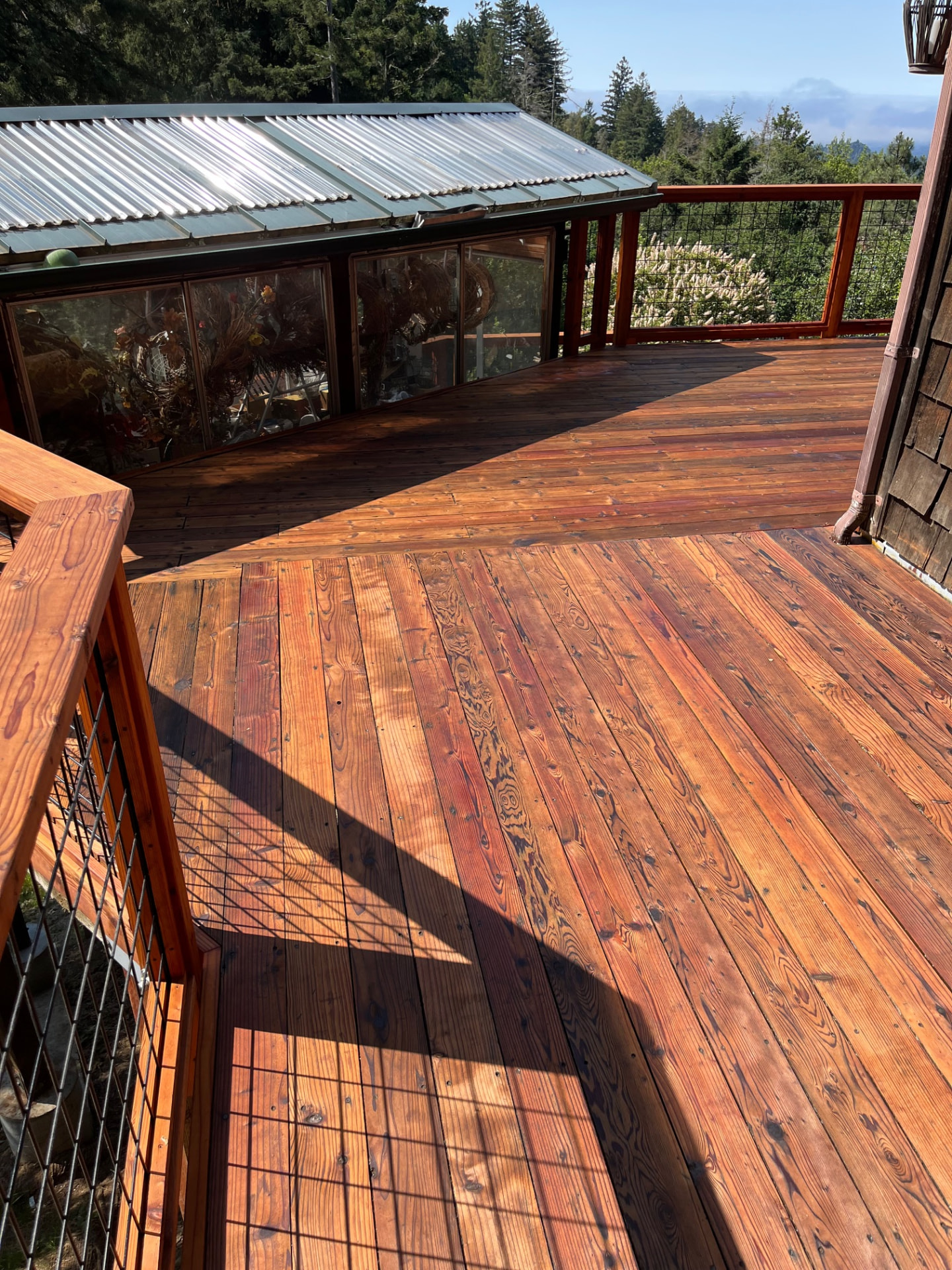 Refinished deck beside a sunroom with hillside views